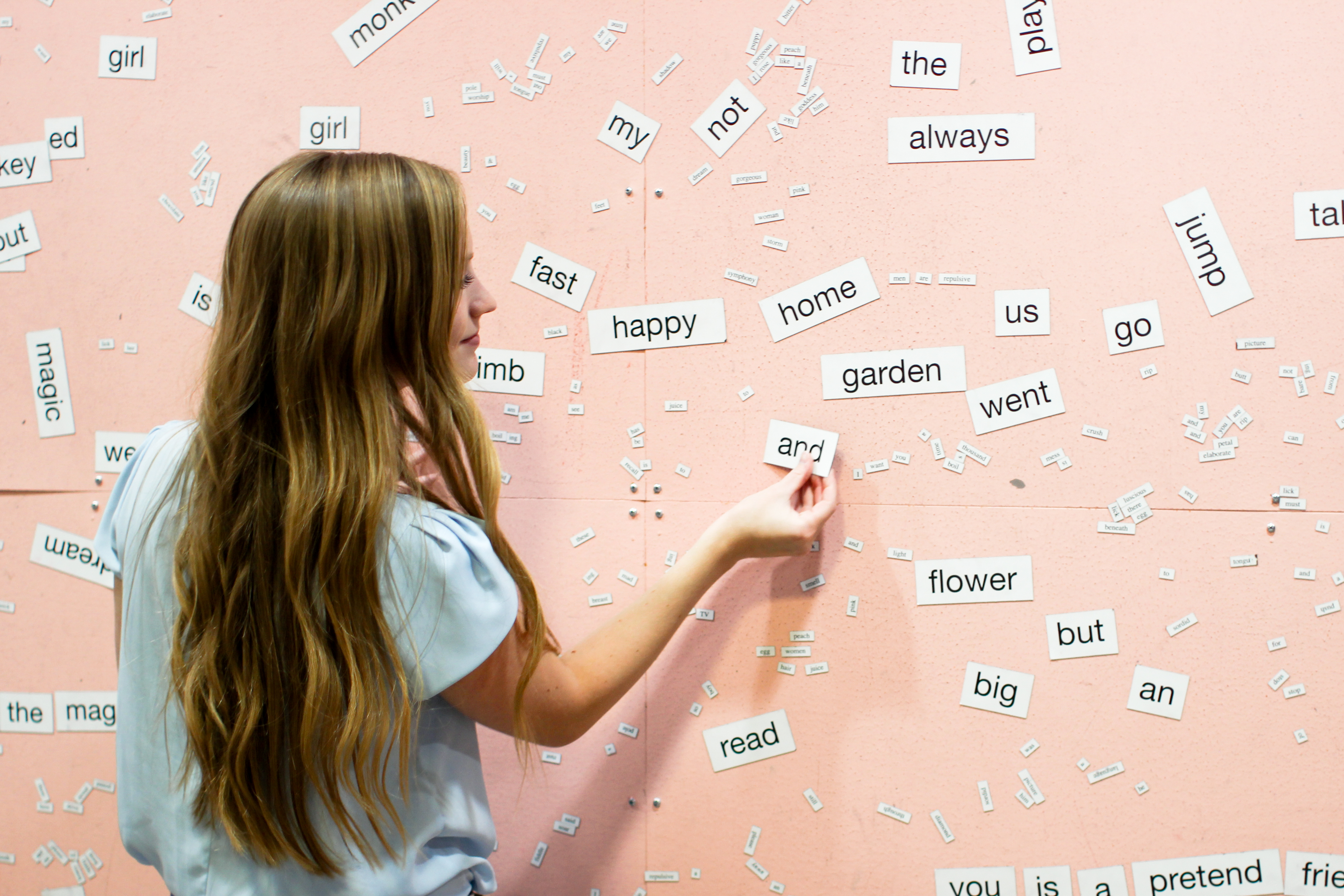 Arranging word magnets on a pink wall at Love Letters Museum in Salt Lake City, Utah