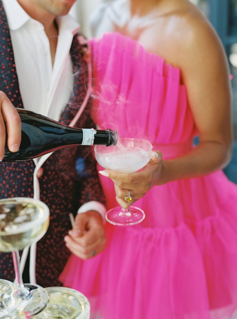 Close-up of a champagne pour by a groom above a champagne tower